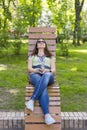 Young woman resting in the park on the bench. Beautiful female relaxing on a park bench Royalty Free Stock Photo