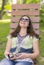 Young woman resting in the park on the bench. Beautiful female relaxing on a park bench Royalty Free Stock Photo