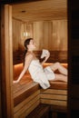 Young woman wearing a bath towel relaxing in sauna at health spa Royalty Free Stock Photo