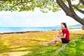 Young woman resting in shade of large canopy tree in Hawaii