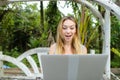 Young woman resting on swing and using laptop, palms in background. Royalty Free Stock Photo