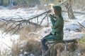 Young woman resting in winter snowy wood with tourist thermos flask outdoors