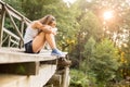 Young woman resting on a wooden bridge in jeans sneakers Royalty Free Stock Photo