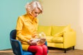 young woman in retro style clothing with golden fish in aquarium sitting on chair at colorful apartment doll Royalty Free Stock Photo