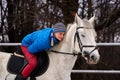 Young woman rider in a blue blazer and sporting a cap for a walk on a white horse Royalty Free Stock Photo