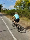 A young woman rides a bicycle along the asphalt road in the park. Active recreation in nature Royalty Free Stock Photo