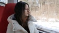 Young woman rides sitting in train and looking thoughtfully out the window