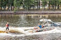 A young woman rides on a water board attached to a boat on the river