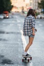 Young woman riding away on a skateboard on an empty city road early in morning Royalty Free Stock Photo