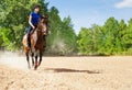 Young woman riding bay horse at sand racetrack Royalty Free Stock Photo