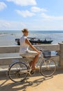 Young woman riding bicycle across river bridge next to tropical park Royalty Free Stock Photo