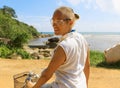 Young woman riding bicycle across river bridge next to tropical park Royalty Free Stock Photo