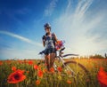 Young woman riding a bicycle on a blooming poppy meadow Royalty Free Stock Photo