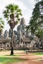 Young woman riding bicycle next to Bayon temple in Angkor Wat complex, Cambodia