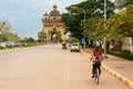 Young woman riding bike near Victory Gate Patuxai Royalty Free Stock Photo