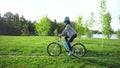 Young woman riding a bike through the park on the background of a lake or river.