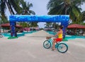 Young woman riding a bike stops in front of a large Welcome to Himmafushi sign Royalty Free Stock Photo