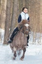 A young woman riding a brown horse on a snowy ground Royalty Free Stock Photo