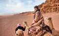 Young woman riding camel in Wadi Rum desert, looking back over her shoulder, smiling. It`s quite cold so she is wearing Royalty Free Stock Photo