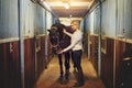 Smiling woman preparing her horse in stables before a ride Royalty Free Stock Photo