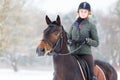 Young woman riding her bay horse on winter field Royalty Free Stock Photo