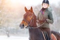 Young woman riding her bay horse on winter field Royalty Free Stock Photo