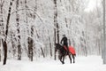 Young woman riding horse on a winter meadow