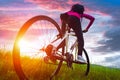 Young woman riding mountain bike on the meadow at sunset Royalty Free Stock Photo