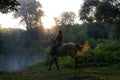 Young woman riding a white horse on a beautiful landscape. Clear lake at morning fog. Royalty Free Stock Photo