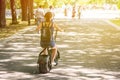 A young woman riding zero-emission eco electric scooter bike in a city park.