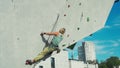 Young woman rock climber climbing on artificial rock wall in outside climbing gym. sports woman working out on extrime