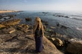 Young woman on the rocky shore of the Atlantic ocean. Travel.