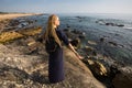 Young woman on the rocky shore of the atlantic ocean