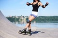 Young woman, roller-blading on rollerdrome. Tan legs, wearing roller-skates and protective equipment, showing the process of