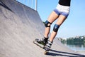 Young woman, roller-blading on rollerdrome. Tan legs, wearing roller-skates and protective equipment, showing the process of