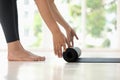 Young woman rolling black yoga mat side view close up