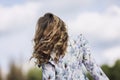 Young woman in a romantic dress with flying hair against the sky, back view. Close-up. Feeling of freedom in unity with nature Royalty Free Stock Photo