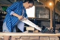 A young woman in the room sawing a Board, a carpenter`s apprentice