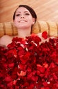 Young woman in rose petal swim water.