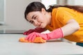 A young woman in rubber gloves is busily wiping the table with a rag. Close-up portrait from the side. House cleaning