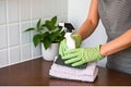 Young woman with rubber gloves cleaning a tiled wall in a light ashy color scheme