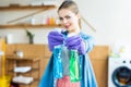 young woman in rubber gloves holding plastic bottles with cleaning fluids and smiling Royalty Free Stock Photo