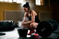 Young woman rubs hands in chalk before lifting barbell Royalty Free Stock Photo