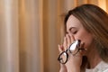 Young woman rubs her eyes, suffers from eye fatigue, holding glasses in her eyes. Royalty Free Stock Photo