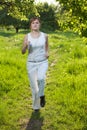 Young woman runing in a park and listen to music