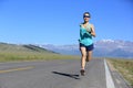 Young woman runner running on sunrise seaside road