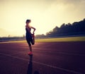 Young woman runner stretching legs before run on stadium track Royalty Free Stock Photo