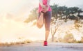 Young woman runner stretching legs before running in sunset rural