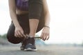 young woman runner tying shoelaces before jogging standing on footpath.