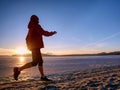 Woman running along shore of a frozen lake in winter spring Royalty Free Stock Photo